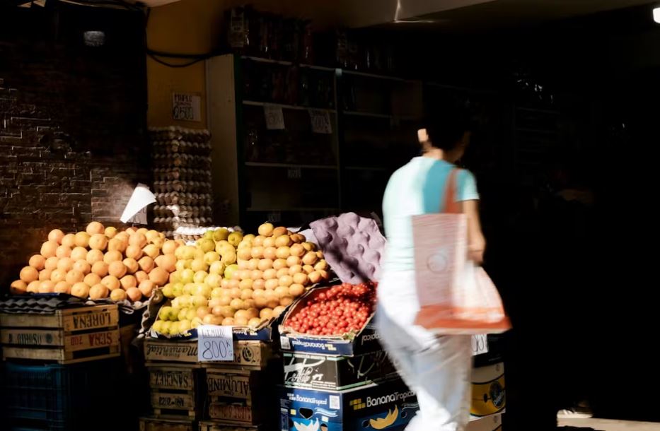 Egy nő sétál egy gyümölcsös stand mellett Buenos Airesben - az élelmiszerárak drámaian megemelkedtek Argentínában az elmúlt évben