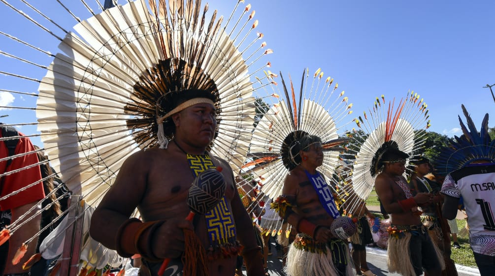 Három őslakos nagy kerek tollkoszorúkkal a fejükön