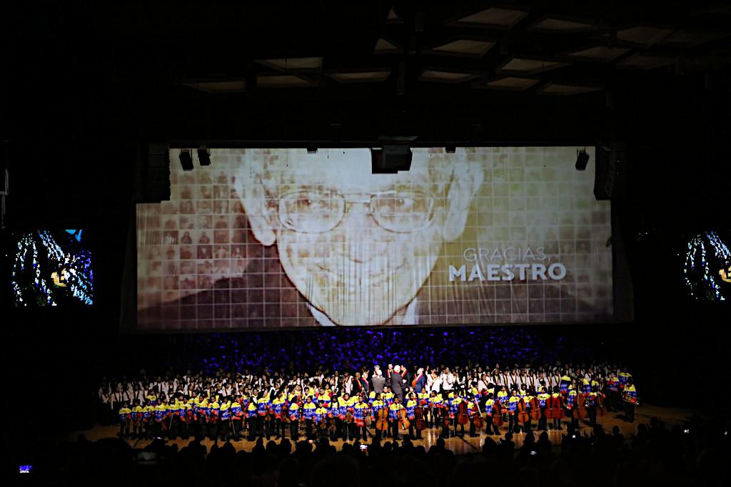 „Multigenerációs” koncert 1200 El Sistema-zenész részvételével a kiállítás végén a Teresa Carreño Színházban. A háttérben José Antonio Abreu portréja