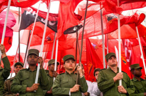 A kubai fegyveres erők tagjai vörös zászlókkal és a „Július 26-i Mozgalom” zászlajával vonulnak az Egyesült Államok havannai nagykövetsége előtt, hogy tiltakozzanak a január 3-i venezuelai támadás és Nicolás Maduro elnök és felesége, Cilia Flores elrablása ellen