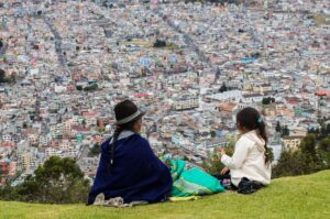 Két nő kukoricát hámozva néz a fővárosra, Quitóra